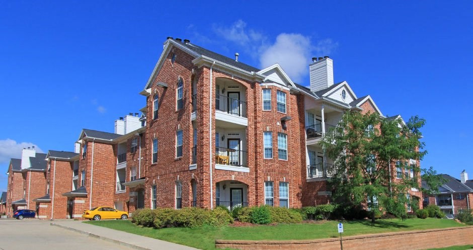 Luxury apartments with red brick exteriors, spacious balconies, lush landscaping, and scenic views at TurtleCreek apartments in West Des Moines, Iowa