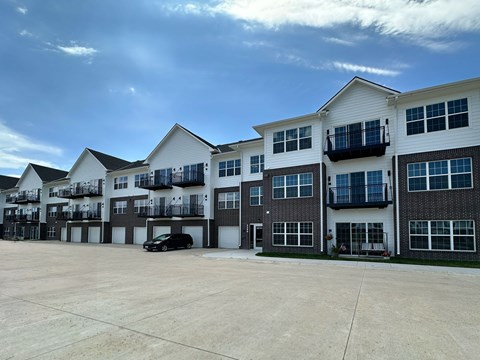 A black car is parked in a parking lot in front of a white building.