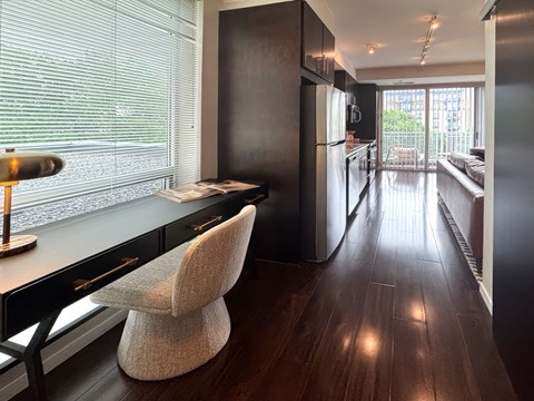 A modern kitchen with dark wood floors and a black refrigerator.