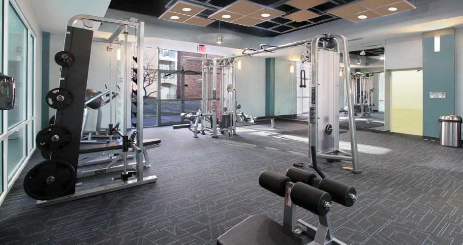 A gym with a variety of equipment including dumbbells and weight machines.