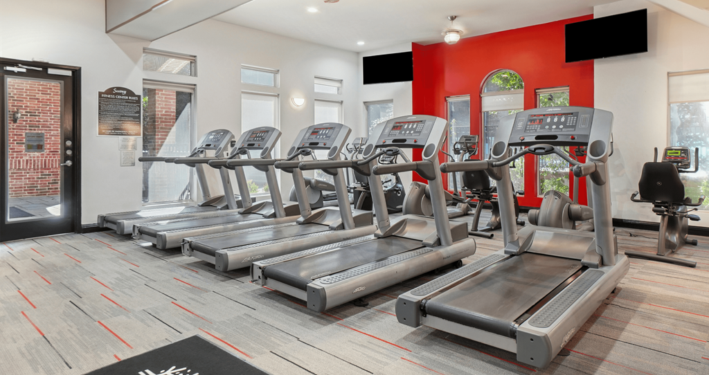 A gym with treadmills and a brick wall.