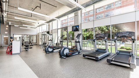 a gym with cardio equipment and windows in a building