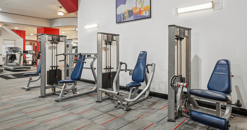 A gym with a variety of equipment including a leg press machine and a rowing machine.