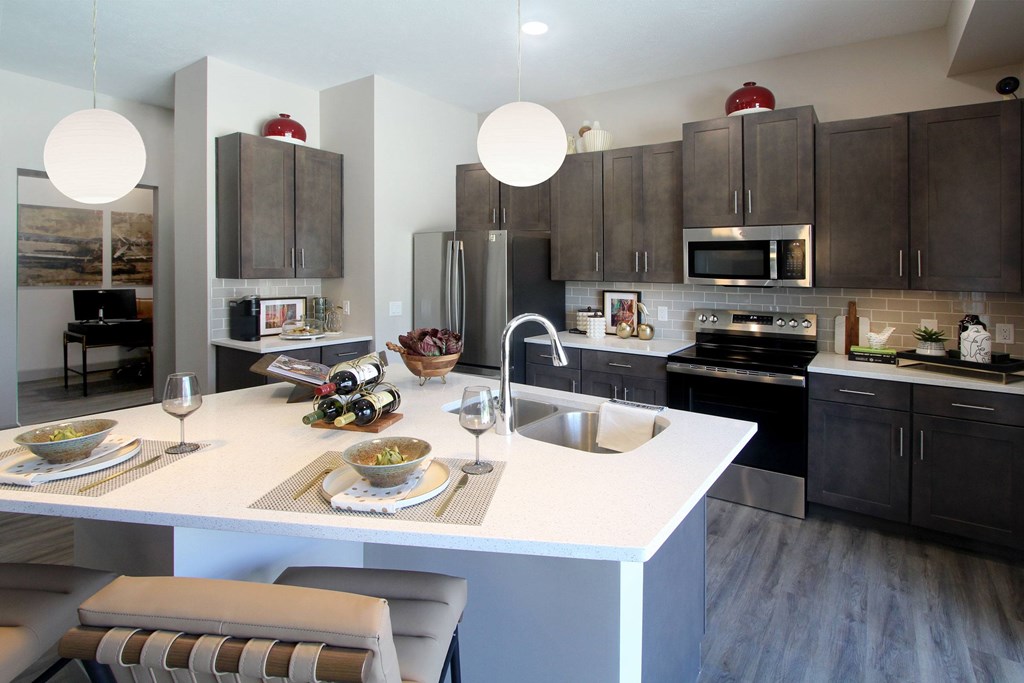 A modern kitchen with a white island and grey cabinets.