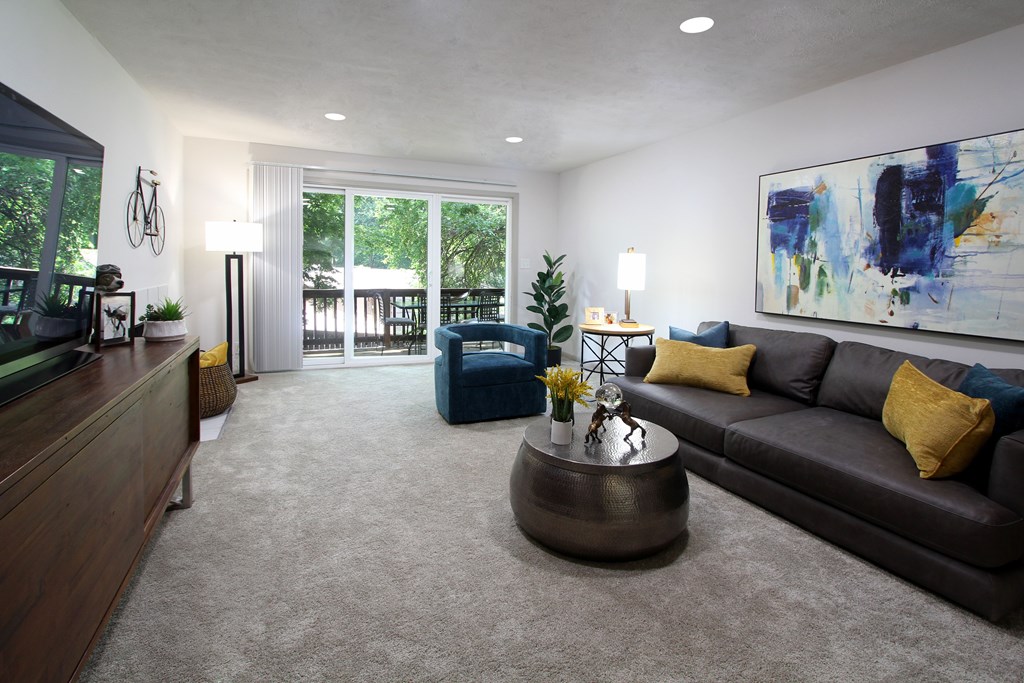 A living room with a brown couch and a painting on the wall.