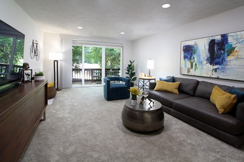 A living room with a brown couch and a painting on the wall.