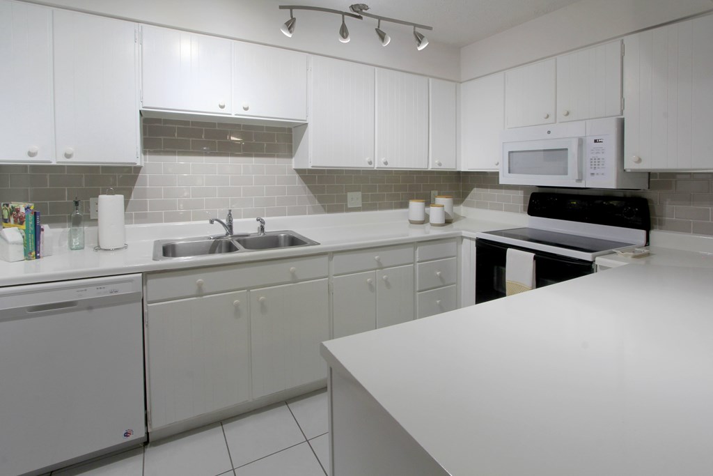 A kitchen with white cabinets and a white counter.