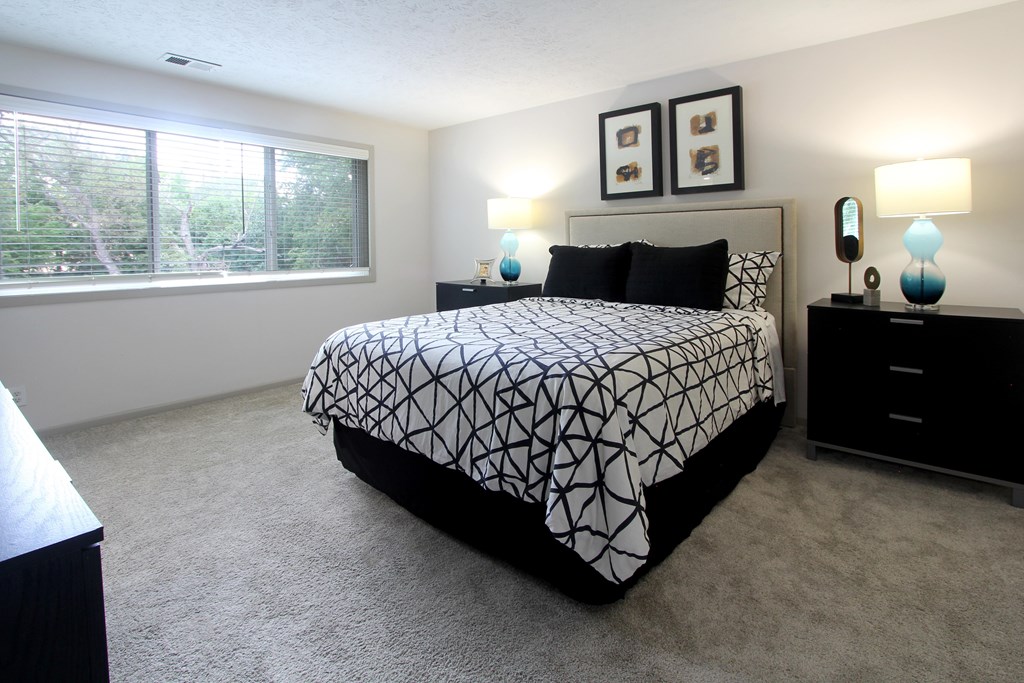 A bedroom with a bed, nightstand, and two wall lamps.