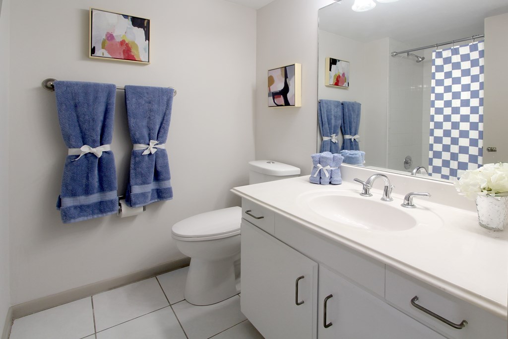 A bathroom with a white toilet, white sink, and blue towels.