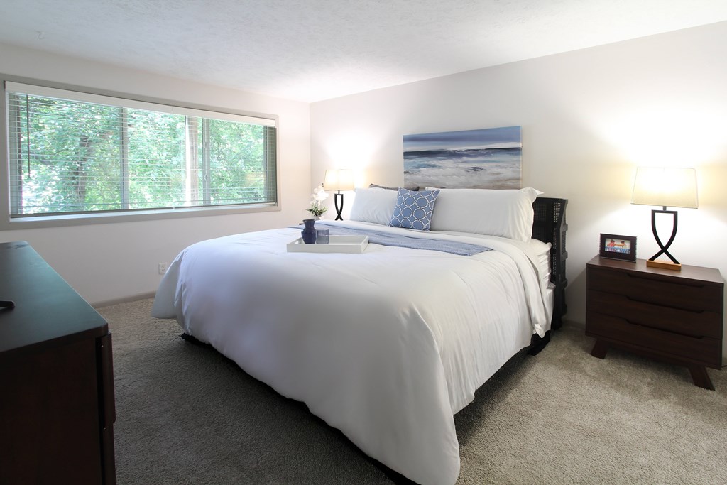 A bedroom with a large bed and a painting on the wall.