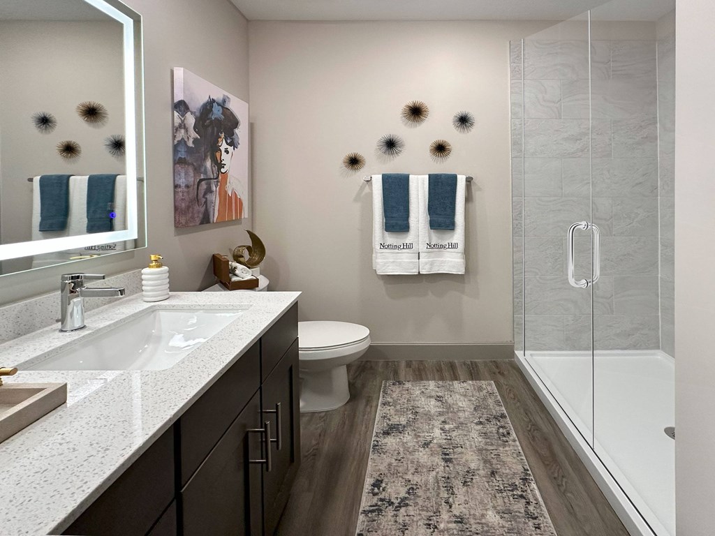 A bathroom with a white sink, toilet, and a glass shower stall.