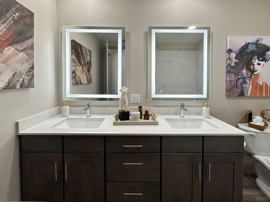A bathroom with two sinks and brown cabinets.