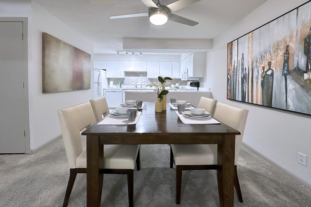 A dining room with a table set for two and a painting on the wall.