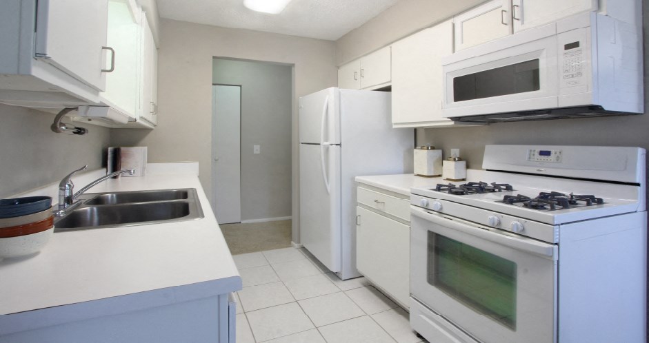 Bright white kitchen with lots of cabinet space and porcelain tile floor at Inwood Apartments in La Vista, Nebraska