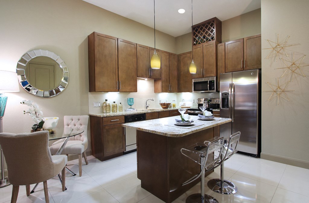 Luxury apartments with spacious kitchen and built-in wine rack, granite countertops, kitchen island, stainless steel appliances, and designer tile backsplash at Tuscany Walk Apartments in Houston Texas.
