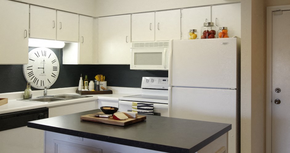 Kitchen with white cabinets, lots of cabinet space, kitchen island, prep island, and colored feature wall at Embassy Park Apartments in Omaha, Nebraska