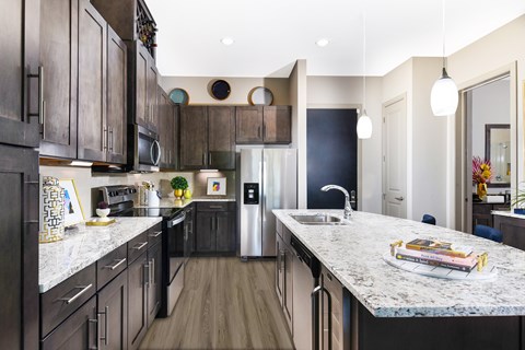 A kitchen with dark wood cabinets and a marble countertop.