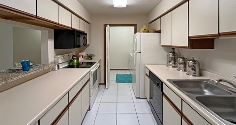 A kitchen with white cabinets and a black microwave.