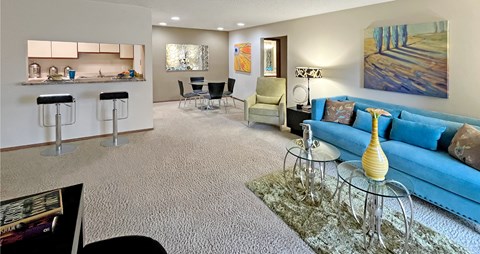 A living room with a blue couch and a glass table.