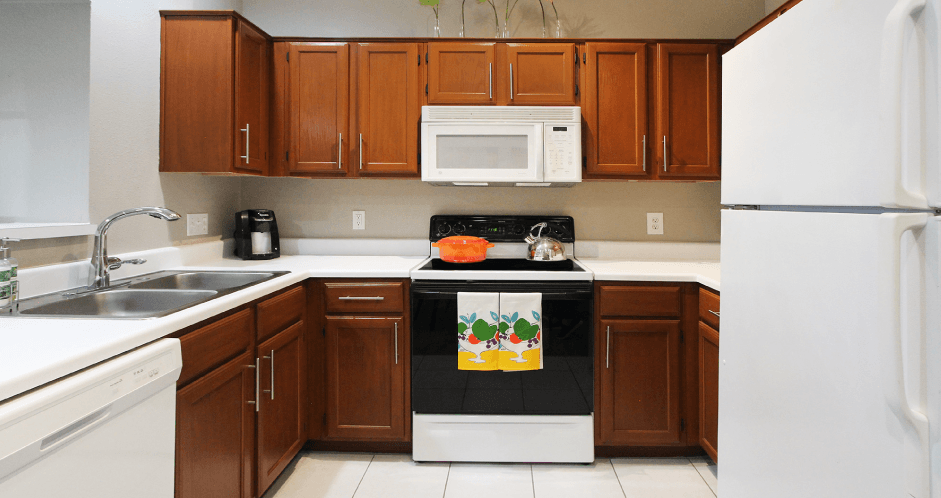 Luxury apartments with honey brown cabinets, tiled floors, white countertops, and u-shaped kitchen at Lenox Village Apartments in Lincoln, Nebraska