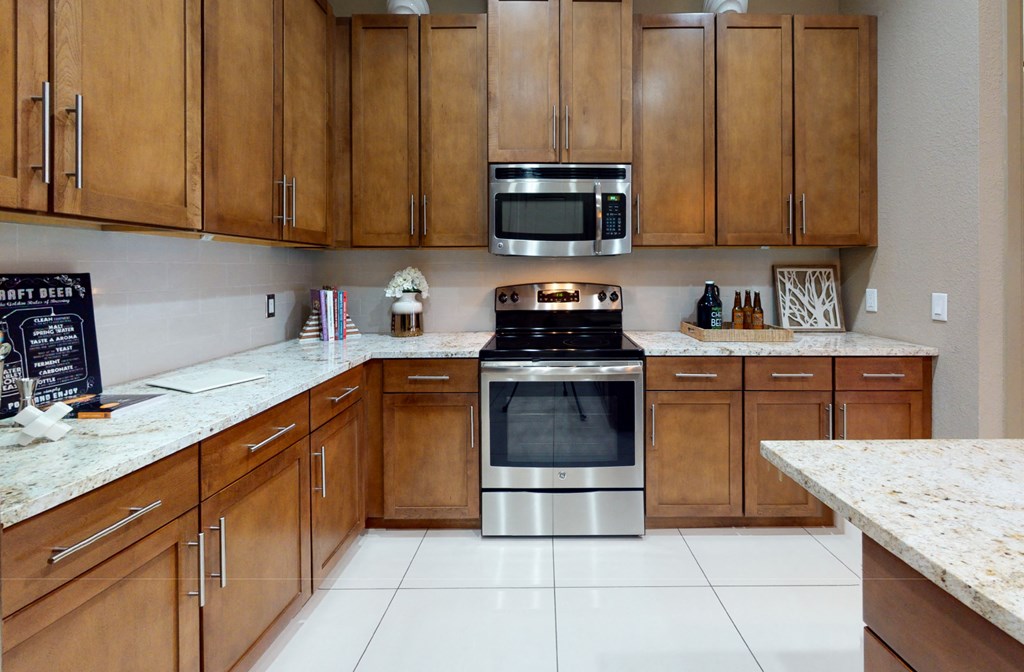 Luxury apartments in Bloomington Minnesota with spacious kitchen, granite countertops, stainless steel appliances, built-in wine rack, kitchen island, and porcelain tile floor at Luxembourg Apartments