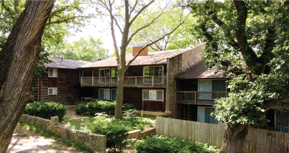a view of the exterior of an old brick house with a yard and trees