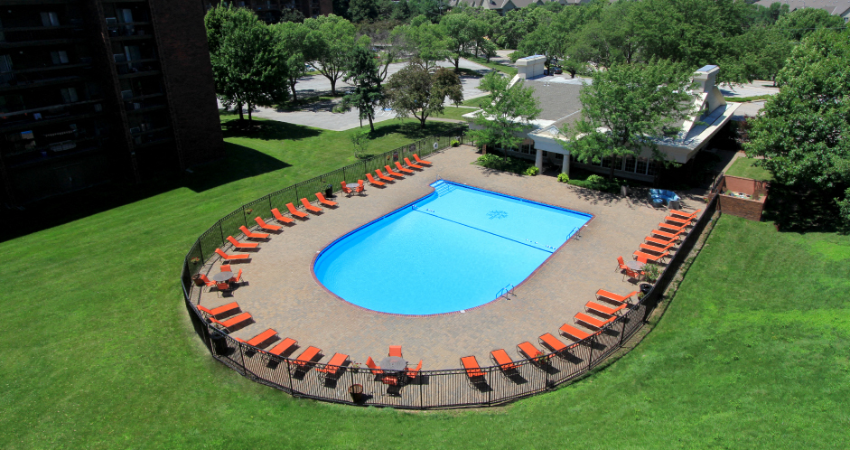 Resort-style saltwater pool with huge sun deck, poolside lounge chairs, and park-like setting with lots of trees and scenic views at Embassy Park Apartments in Omaha, Nebraska