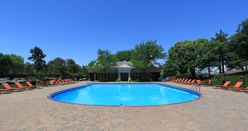 Resort-style saltwater pool with huge sun deck, poolside lounge chairs, and park-like setting with lots of trees and scenic views at Embassy Park Apartments in Omaha, Nebraska