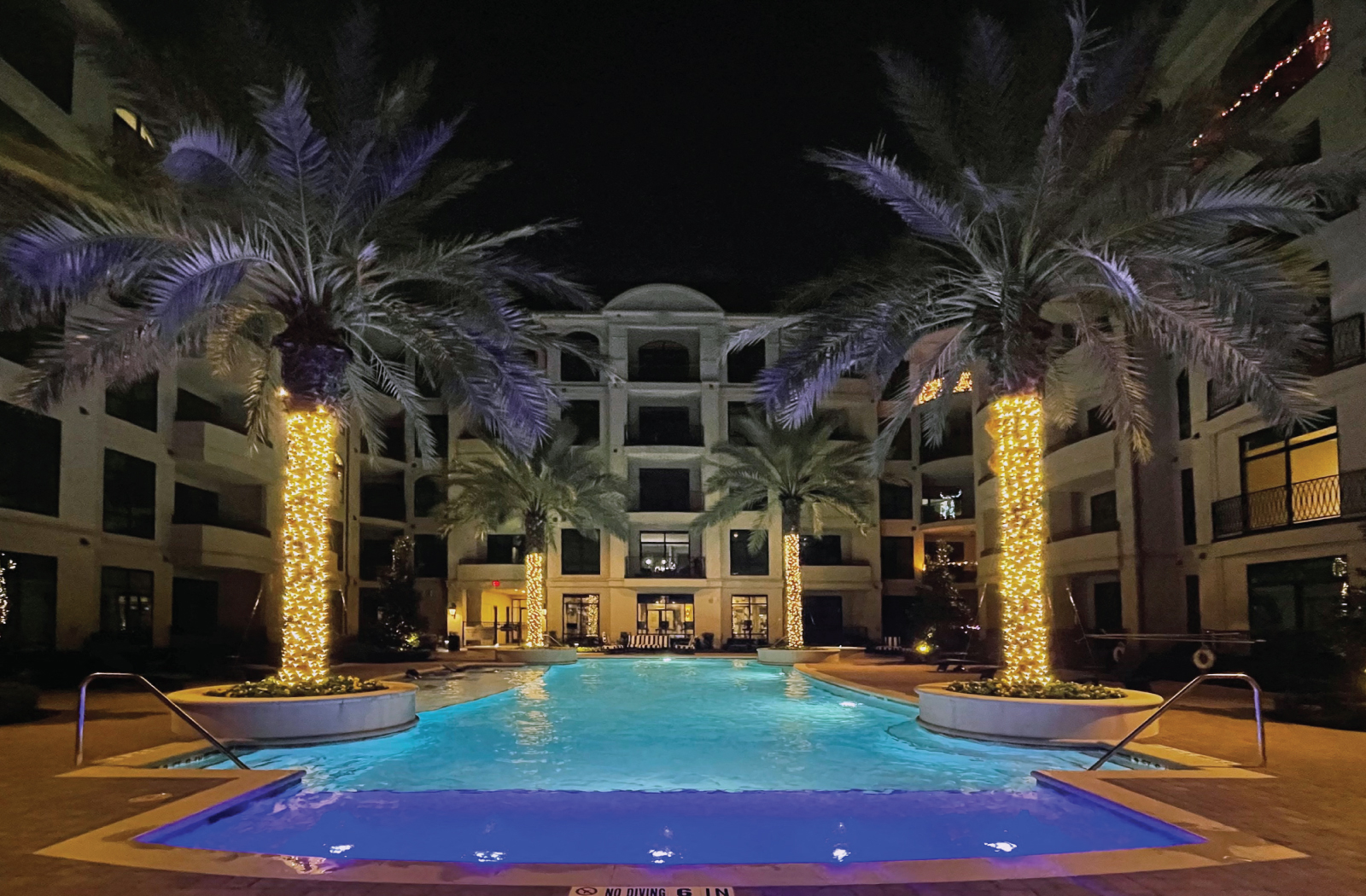 Luxury apartments with resort-style pool with palm trees, Baja shelf, fountains, lap lane, outdoor lounges, and grilling station at Le Palais Apartments in Houston.