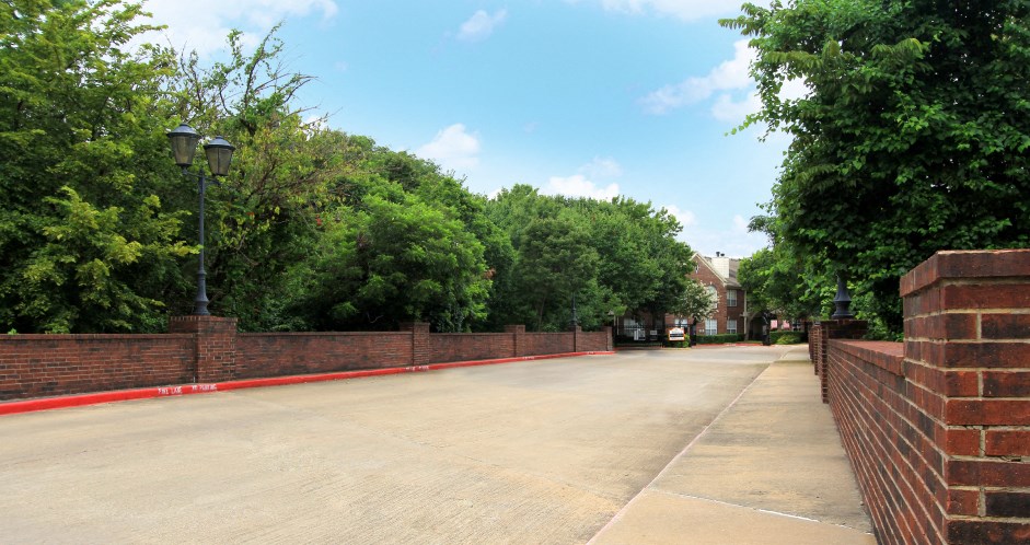 an empty street with a brick wall and trees