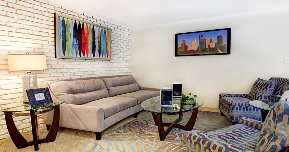Spacious living room with white brick feature wall at Plantation apartments near the Galleria in Houston.