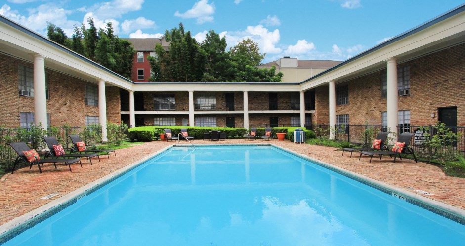 Apartments near the Galleria with multiple swimming pools, sun deck with poolside lounge chairs, brick exteriors and courtyard setting at Plantation apartments in Houston.