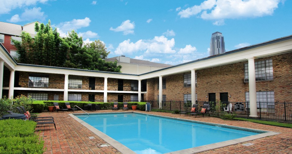 Apartments near the Galleria with multiple swimming pools, sun deck with poolside lounge chairs, brick exteriors and courtyard setting at Plantation apartments in Houston.