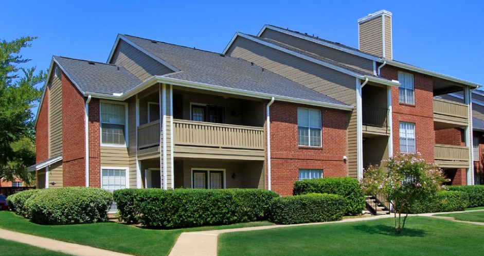 Luxury apartments with red brick exteriors, beautiful landscaping, and spacious balconies at Preston Village Apartments in North Dallas
