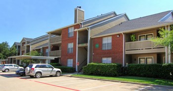 Luxury apartments with red brick exteriors, beautiful landscaping, and spacious balconies at Preston Village Apartments in North Dallas - Photo Gallery 9