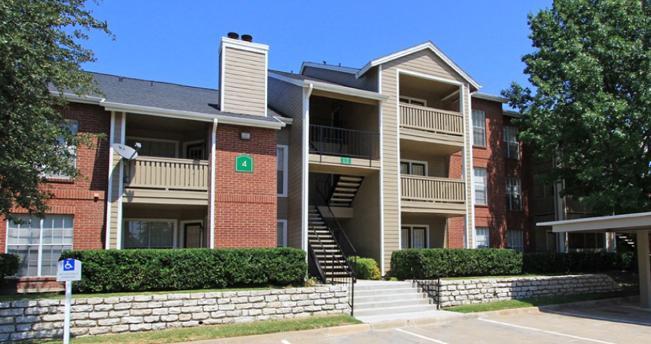Luxury apartments with red brick exteriors, beautiful landscaping, and spacious balconies at Preston Village Apartments in North Dallas