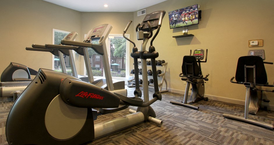 Luxury apartments with a fitness center in a gated community at Preston Village Apartments in North Dallas