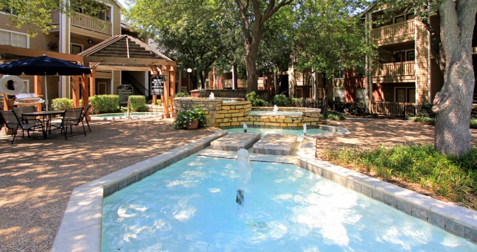 Luxury apartments with beautiful fountains, beautiful landscaping, gazebo, spa and swimming pool with poolside lounge chairs, grilling station and scenic views at Preston Village Apartments in north Dallas