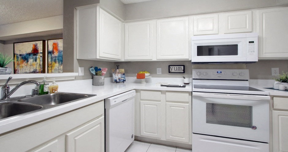 Bright white kitchen with tile floors at Preston Village Apartments in north Dallas
