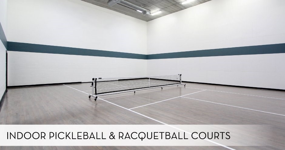 An indoor pickleball and racquetball court with a net and two paddles.