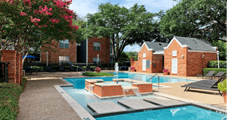 Luxury apartments with two swimming pools with fountain, poolside lounge chairs, and beautiful landscaping in Dallas.