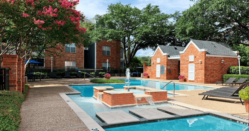 Luxury apartments with two swimming pools with fountain, poolside lounge chairs, and beautiful landscaping in Dallas. - Photo Gallery 1