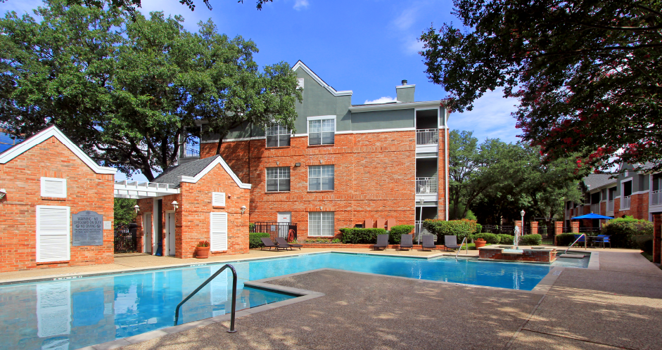 Luxury apartments with two resort-style swimming pools with fountain, poolside lounge chairs, and beautiful landscaping in Dallas.