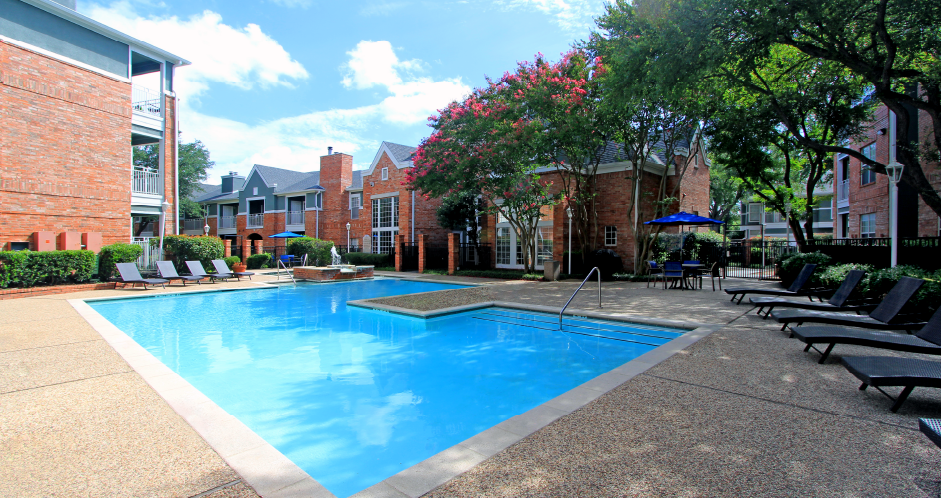 Luxury apartments with two resort-style swimming pools with fountain, poolside lounge chairs, and beautiful landscaping in Dallas.