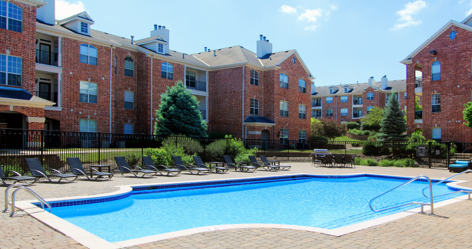 Luxury apartments with red brick exterior, huge swimming pool, poolside lounge chairs, grilling station, and lush landscaping at TurtleCreek apartments in West Des Moines, Iowa
