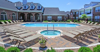 Luxury apartments with red brick exteriors, swimming pool, pool-side lounge chairs, beautiful landscaping, and scenic views at Rockledge Oaks Apartments in Lincoln, Nebraska - Photo Gallery 4