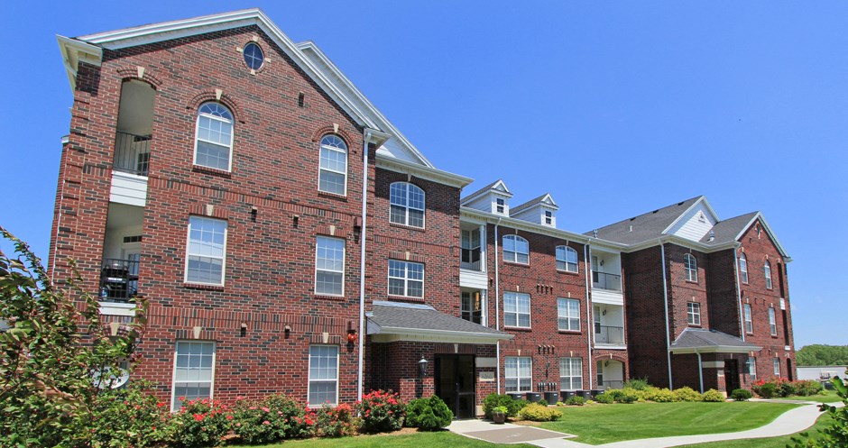 Luxury apartments with red brick exteriors, beautiful landscaping, and scenic views at Rockledge Oaks Apartments in Lincoln, Nebraska