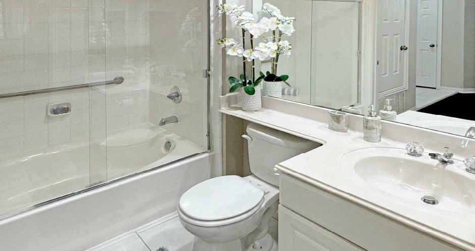 Luxury bathroom with tiled floors, oval soaking tub, built-in vanity, cultured marble vanity, glass shower and white cabinets in at Saddlebrook apartments in Urbandale Iowa