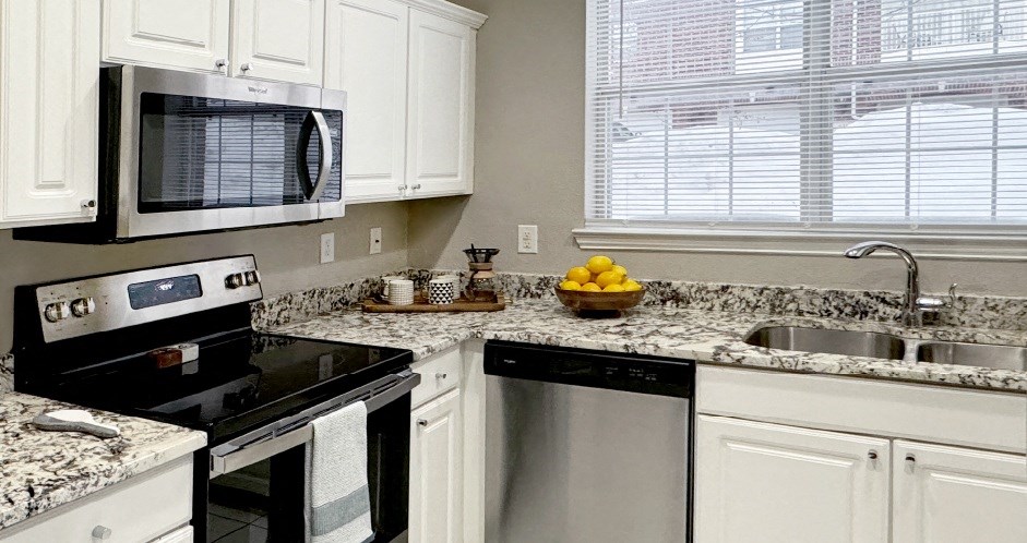 Luxury apartments with granite countertops, white cabinets, stainless steel appliances, and side-by-side refrigerator at Saddlebrook apartments in Urbandale Iowa