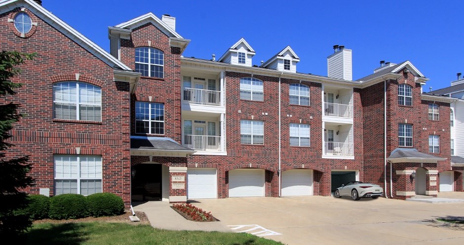 A large red brick apartment building with multiple garages and balconies.